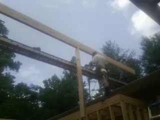 Carpenter setting a ridge beam over a new addition frame — Ice Dam Removal by Roofing Brothers in Westfield Center