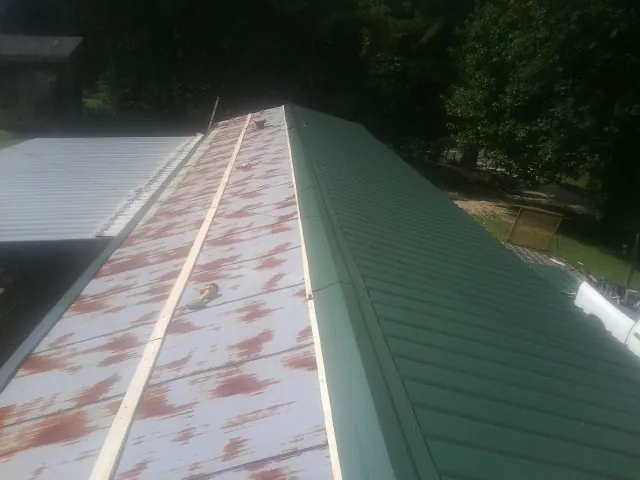 Old rusted panels beside newly installed green metal roofing — Wind Damage Roof Repair by Roofing Brothers in Westfield Center
