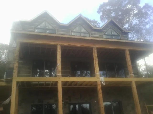 Dormers and porch framing on a large log home under construction — Roof Coating work by our crew in Westfield Center