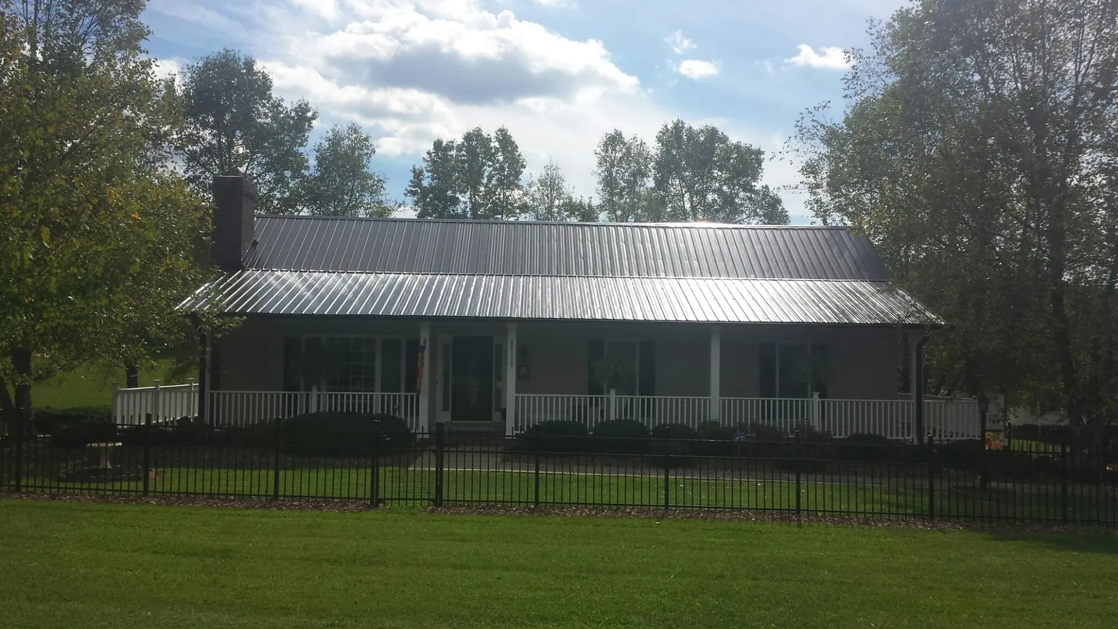 Gray metal roof on a brick ranch with a full width front porch — Gutter Guard Installation work by our crew in Westfield Center