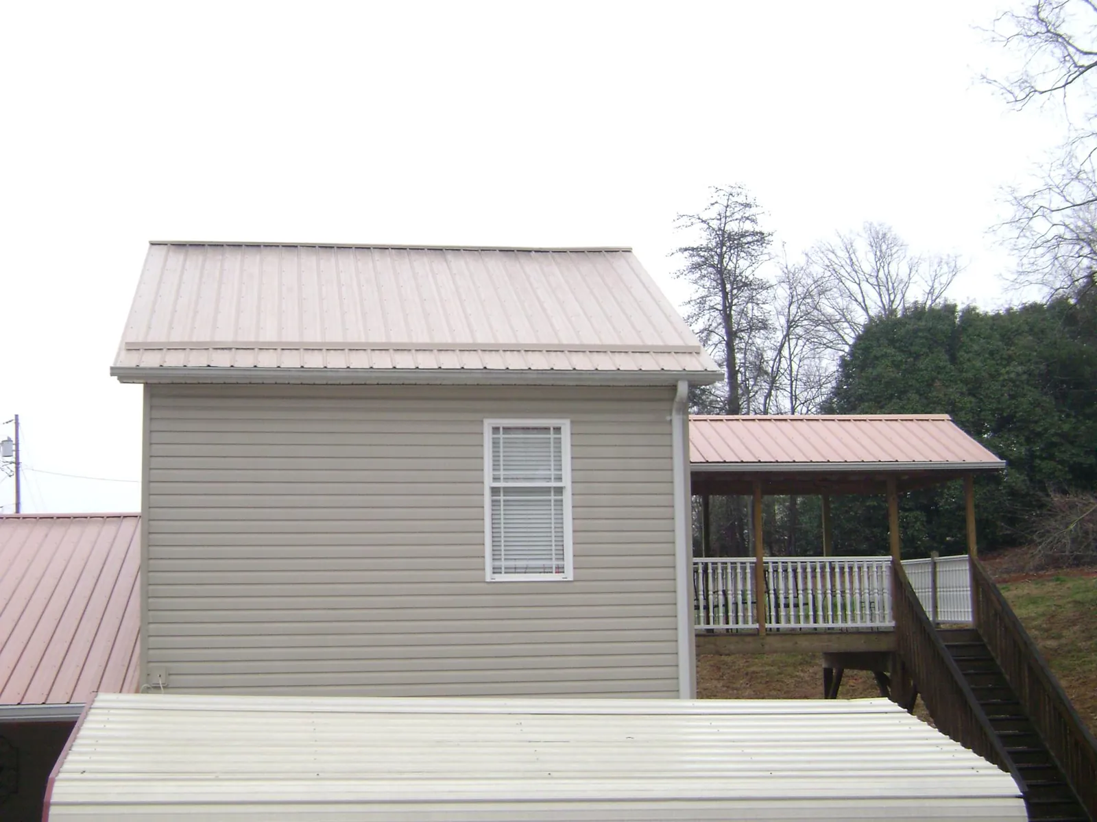 Tan metal roofs on a two story addition and attached porch, from a Roof Replacement job in Westfield Center