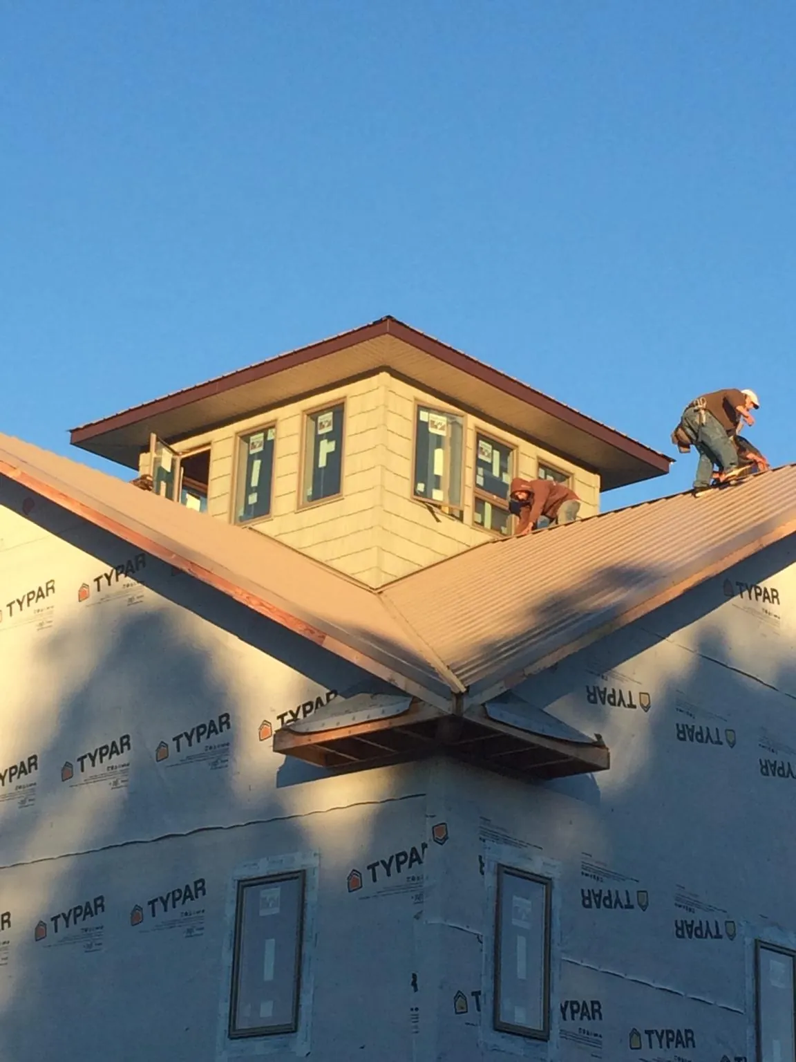 Roofers working around a rooftop cupola on a new metal roof at sunset — Roof Waterproofing in Westfield Center by Roofing Brothers
